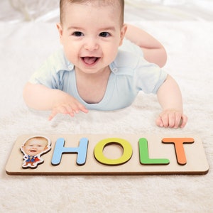 May include: A personalized wooden puzzle with the name "HOLT" spelled out in colorful letters. A photo of a baby is included in the puzzle.