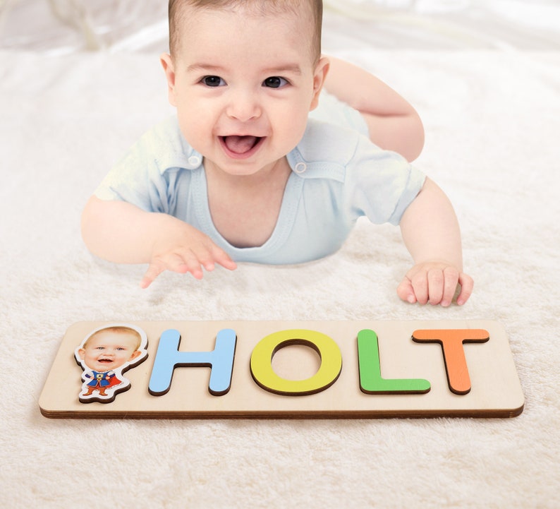 May include: A personalized wooden puzzle with the name "HOLT" spelled out in colorful letters. A photo of a baby is included in the puzzle.