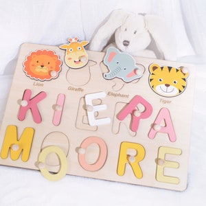 May include: Wooden puzzle with colorful animal and letter pieces. The puzzle is shaped like a rectangle and has a light wood finish. The letters spell out the name "KIERA MOORE".