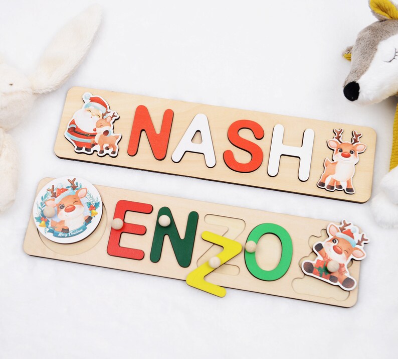 May include: Two wooden puzzle boards with Christmas themes. The top board spells out the name "NASH" with a Santa Claus and reindeer illustration. The bottom board spells out the name "ENZO" with a reindeer illustration.