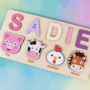 May include: A wooden puzzle featuring the name SADIE spelled out in colourful letters. The puzzle also includes images of a pig, cow, chicken, and horse.