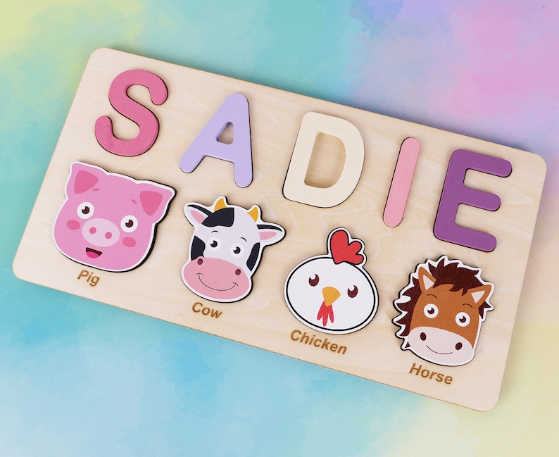 May include: A wooden puzzle featuring the name SADIE spelled out in colourful letters. The puzzle also includes images of a pig, cow, chicken, and horse.
