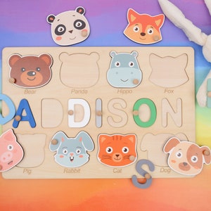 May include: A wooden puzzle board with colorful animal illustrations and the name "DADDISON" spelled out in letter blocks. The puzzle pieces are shaped like animals, including a bear, panda, hippo, fox, pig, rabbit, cat, and dog.