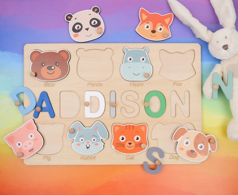 May include: A wooden puzzle board with colorful animal illustrations and the name "DADDISON" spelled out in letter blocks. The puzzle pieces are shaped like animals, including a bear, panda, hippo, fox, pig, rabbit, cat, and dog.