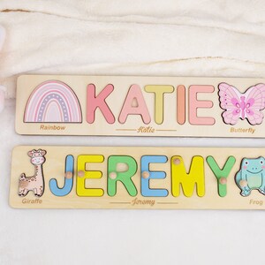 May include: Two wooden personalized puzzle boards with colorful letters spelling out the names Katie and Jeremy. Each board features a different animal and object: a rainbow, butterfly, giraffe, and frog.