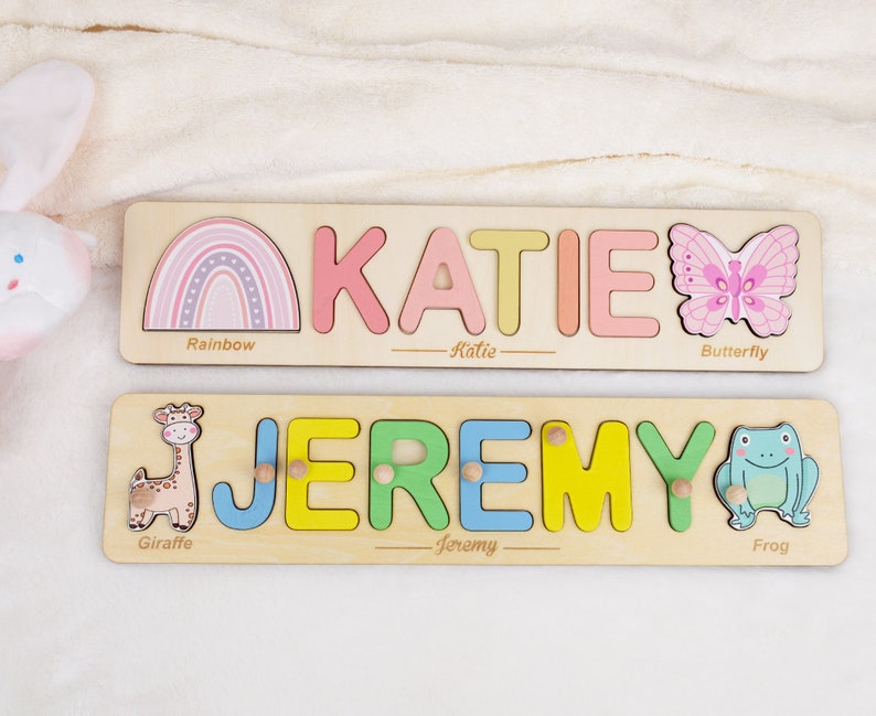 May include: Two wooden personalized puzzle boards with colorful letters spelling out the names Katie and Jeremy. Each board features a different animal and object: a rainbow, butterfly, giraffe, and frog.