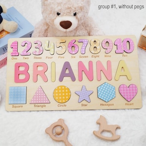 Op de afbeelding: Een houten puzzelbord met de cijfers &eacute;&eacute;n tot en met tien, de naam BRIANNA in grote letters en zes vormen met de labels square, triangle, circle, star, hexagon en heart. De puzzelstukjes zijn versierd met verschillende pastelkleurige patronen.
