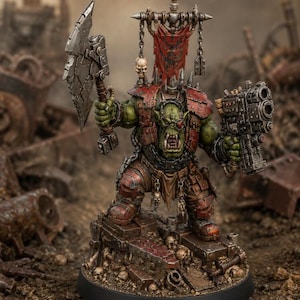 May include: A green-skinned orc miniature figure standing on a debris-filled base. The figure wears red armour plates, carries a large metallic axe in one hand and a heavy firearm in the other, and features a red banner with a skull icon.