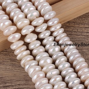 May include: A strand of white freshwater pearls, each pearl is a slightly off-round shape and has a smooth, glossy finish. The pearls are strung on a clear thread and are arranged in a staggered pattern.