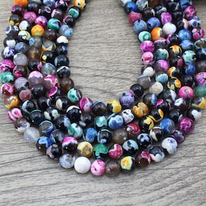 May include: A strand of colorful agate beads with black and white patterns. The beads are round and have a smooth, polished finish.