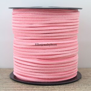 May include: A spool of pink suede cord, perfect for jewelry making or crafting projects. The cord is wound tightly on a black spool.