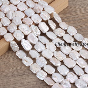 May include: A strand of white baroque freshwater pearl beads. The pearls are irregularly shaped and have a slightly iridescent sheen. The beads are strung on a white thread and are approximately 10mm in size.