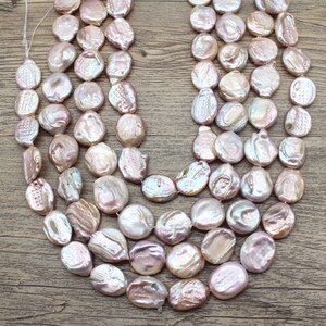 Può includere: Un filo di perle d'acqua dolce rosa iridescenti, ogni perla ha una forma irregolare e unica. Le perle sono infilate su un cordoncino bianco e sono pronte per essere utilizzate per la creazione di gioielli.