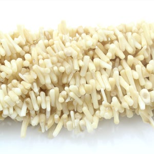 May include: A strand of off-white coral beads. The beads are small and cylindrical, with a rough, natural texture.