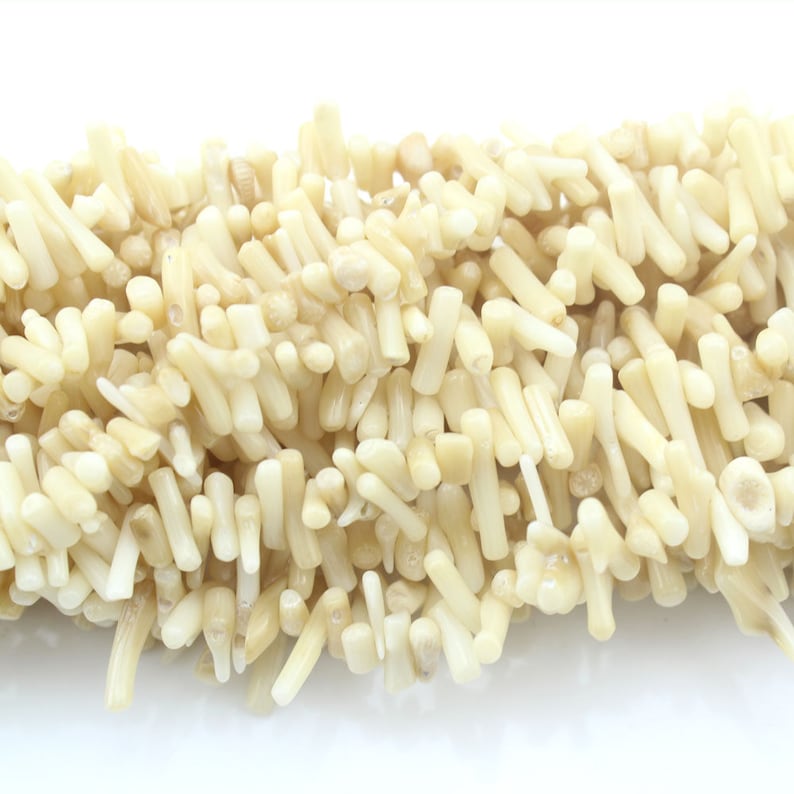 May include: A strand of off-white coral beads. The beads are small and cylindrical, with a rough, natural texture.
