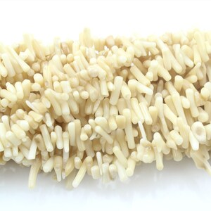 May include: A strand of white coral beads, each bead is a long, thin, irregular shape.