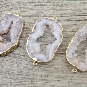 Puede incluir: Tres rebanadas de ágata blanca con detalles metálicos dorados. Cada rebanada tiene una forma natural irregular con un gran centro abierto. Las rebanadas son perfectas para la elaboración de joyas o manualidades.