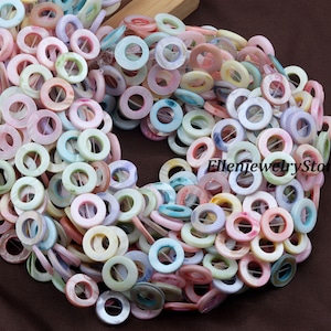 May include: A collection of colorful, ring-shaped beads in various pastel shades, including pink, blue, yellow, and green. The beads are strung together, creating a textured and visually appealing display. The beads are made of a shiny material.