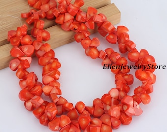 May include: A strand of bright orange coral beads, each bead is a unique, irregular shape. The beads are strung on a clear thread and are ready to be used in jewelry making.