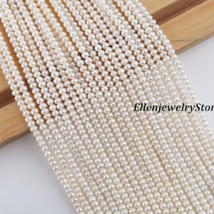 Könnte beinhalten: Nahaufnahme von mehreren Strängen kleiner, weißer Perlen. Die Perlen sind gleichmäßig groß und geformt und erzeugen eine glatte, glänzende Oberfläche. Der Hintergrund ist eine hellfarbige Holzoberfläche. Der Text "EllenjewelryStore" ist sichtbar.