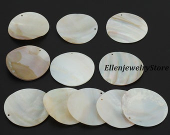 May include: A collection of iridescent, round, mother-of-pearl shell pendants. Each pendant has a small hole for stringing. The pendants vary slightly in color, with hints of cream, pink, and gold. The text "EllenjewelryStore" is visible.