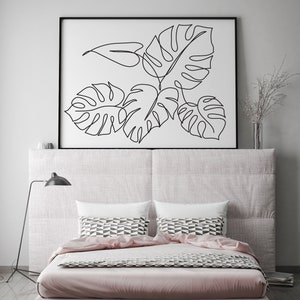 May include: A black and white line drawing of tropical leaves in a black frame above a bed with a pink duvet and patterned pillows.