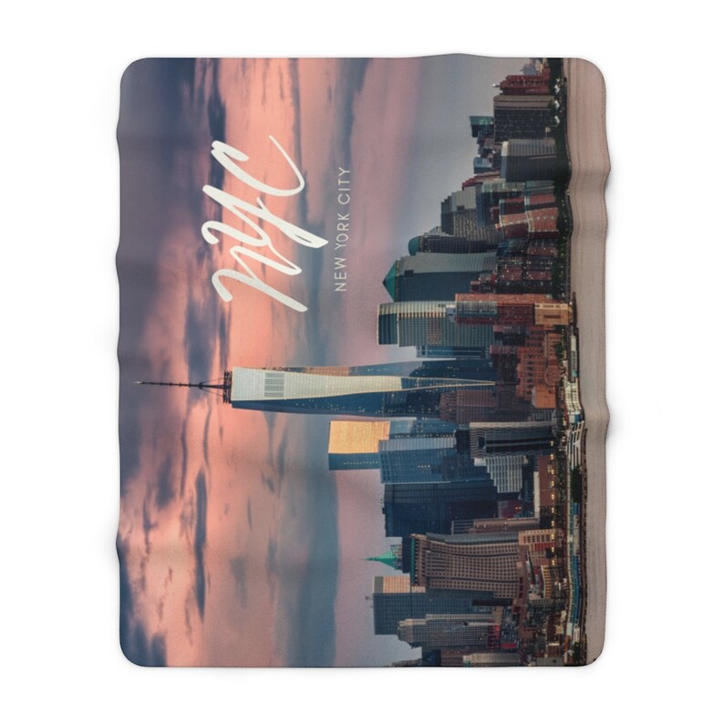 May include: A panoramic view of the New York City skyline at sunset, with the Freedom Tower prominently featured. The text "NYC NEW YORK CITY" is written in white script across the image.