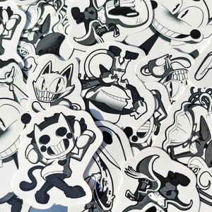 以下が含まれることがあります： 白黒の漫画キャラクターのステッカーのコレクション。ステッカーは、さまざまな表情とポーズのキャラクターを特徴としています。ステッカーは白い紙に印刷されており、光沢のある仕上げになっています。