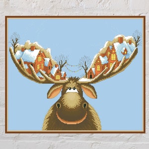Puede incluir: Un alce marrón con una cara amigable tiene casas con techos cubiertos de nieve en sus astas. El fondo es un cielo azul claro.