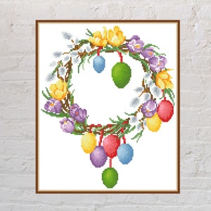 May include: A colorful Easter wreath with purple, yellow, and white flowers, green leaves, and a variety of colored eggs hanging from it.