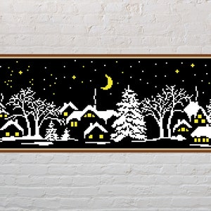 May include: A black and white pixel art cross stitch pattern of a snowy village scene at night. The scene includes houses with lit windows, trees, and a crescent moon in the sky.