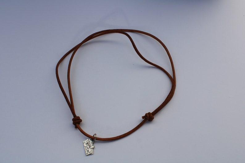 Może przedstawiać: Brązowy sk&oacute;rzany naszyjnik z zawieszką z napisem "LOVE" wykonaną ze srebra.