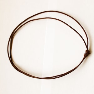 Peut inclure: Un collier en cordon de cuir marron avec une fermeture simple à nœud.