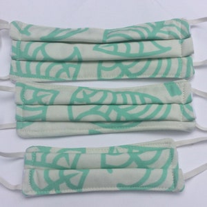 May include: Three white face masks with a light green leaf pattern. The masks are pleated and have white elastic ear loops.