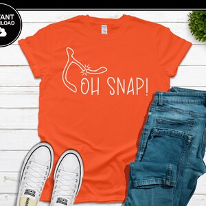 May include: An orange t-shirt with the phrase "OH SNAP!" in white, along with a wishbone graphic. The shirt is paired with blue jeans and white sneakers. A black and white "INSTANT DOWNLOAD" graphic is in the upper left corner.