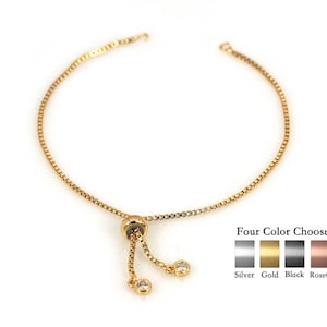 May include: A gold chain bracelet with a sliding clasp and two small clear stones. The bracelet is available in four colors: silver, gold, black, and rose gold.
