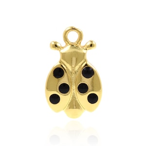 May include: Gold-colored ladybug charm with black enamel spots. The charm has a loop at the top for attaching to a necklace or bracelet.