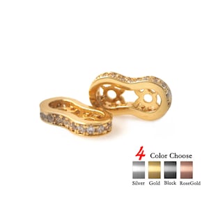 May include: Two gold-toned metal connector pieces with clear crystal accents. The connector pieces are shaped like a peanut and have a hole in the centre. The image shows four colour options: silver, gold, black, and rose gold.
