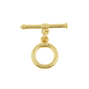 Puede incluir: Un cierre de palanca dorado, que consta de una barra en T y un anillo circular. El cierre está diseñado para la fabricación de joyas y se muestra sobre un fondo blanco. El metal tiene un acabado brillante, reflejando la luz.