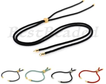 Könnte beinhalten: Ein Set aus vier verstellbaren Kordelarmbändern mit goldfarbenen Verschlüssen. Die Armbänder sind in Schwarz, Grau, Türkis und Rot erhältlich.