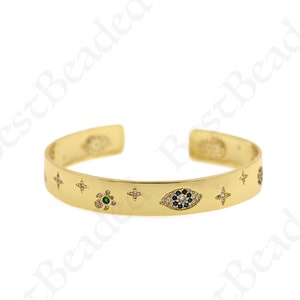Könnte beinhalten: Goldenes Armreif-Armband mit einem blauen bösen Augen-Anhänger und anderen kleinen Anhängern, darunter Sterne und Blumen. Die Anhänger sind mit klaren und farbigen Edelsteinen besetzt.