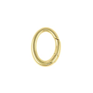 May include: A gold-coloured oval clasp, possibly for jewellery or accessories, is shown against a white backdrop. The clasp has a smooth, shiny finish and a hinged section for opening and closing. The design is simple and elegant.
