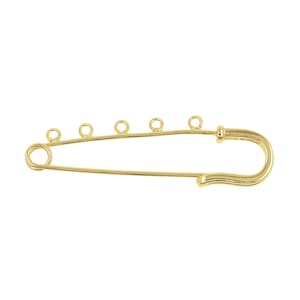 Puede incluir: Un imperdible de color dorado con cinco pequeños bucles unidos a lo largo del eje del imperdible. El imperdible tiene un diseño sencillo y elegante, adecuado para la fabricación de joyas o proyectos de artesanía. El imperdible está sobre un fondo blanco.