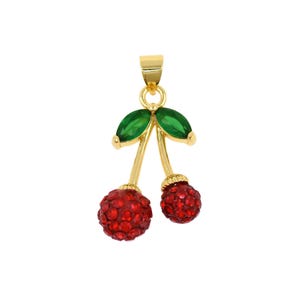 May include: A gold-colored pendant in the shape of cherries. The pendant features two red, crystal-studded cherry spheres, green leaf accents, and a gold-colored bail for hanging. The pendant is designed to be worn as jewelry.