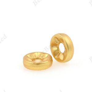 May include: Two gold-colored metal beads with a raised center and a hole in the center.