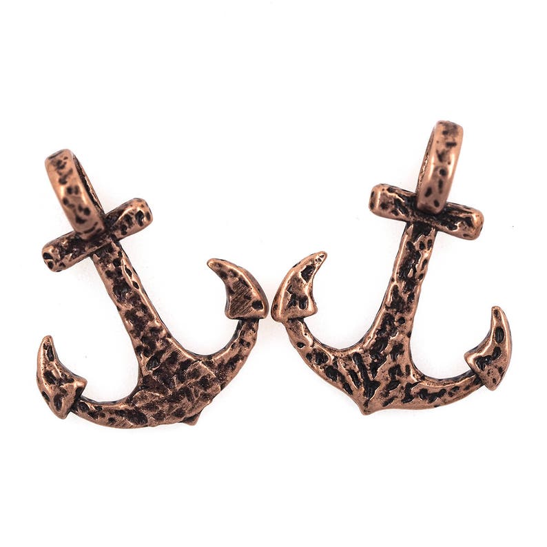 May include: Two antique copper-coloured anchor charms with a textured surface.