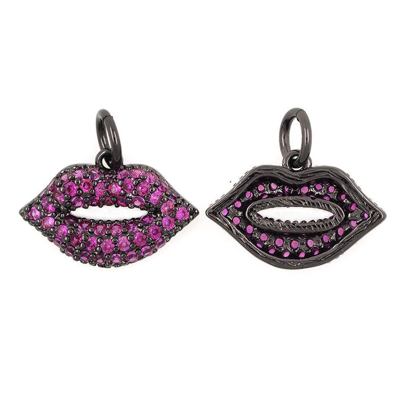May include: Two black metal charms in the shape of lips, one with pink rhinestones and the other with a black outline and pink rhinestones.