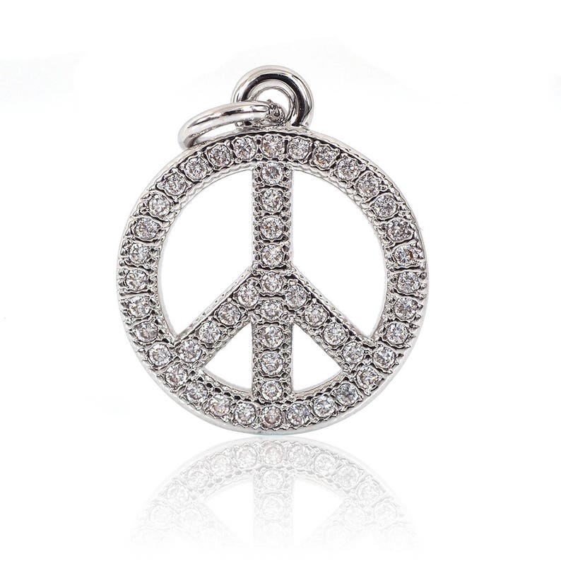 May include: A silver peace sign charm with clear rhinestones. The charm is a popular symbol of peace and love.