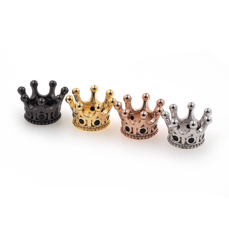 May include: Four small crown-shaped metal charms in black, gold, rose gold, and silver.