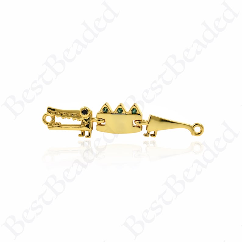 Puede incluir: Encanto de cocodrilo dorado con detalles de piedras preciosas verdes. El encanto est&aacute; dise&ntilde;ado para ser utilizado como conector para la elaboraci&oacute;n de joyas.
